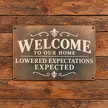 WELCOME TO OUR HOME LOWERED EXPECTATIONS EXPECTED — Metal Sign